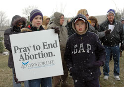 St. Malachy parishioners Zachary Duckett, left, and Owen Duckett of Brownsburg pray in front of the Planned Parenthood abortion center in Indianapolis on Feb. 22 as part of the “40 Days for Life” spring prayer campaign. The brothers were among a number of youths who prayed the rosary for an end to abortion. (Photo by Mary Ann Wyand) 