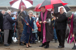 Archbishop Daniel M. Buechlein and Franciscan Sister Shirley Gerth, parish life coordinator of St. Anne Parish in New Castle, break ground for the new $4.4 million church on March 29 with help from, left to right, St. Anne parishioner Jack Basler, building committee chair, back to camera; New Castle Mayor James Small; Michael Witka, director of risk management for the archdiocese; and Father Joseph Rautenberg, sacramental minister for the Henry County faith community. (Photo by Mary Ann Wyand) 