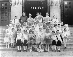 Father Augustine Sansone, fourth from left in the back row, stands on the steps of Our Lady of the Most Holy Rosary Church in Indianapolis after his first Mass on May 26, 1929. The parish’s founding pastor, Father Marino Priori, stands second from left in the back row. (Archive photo) 