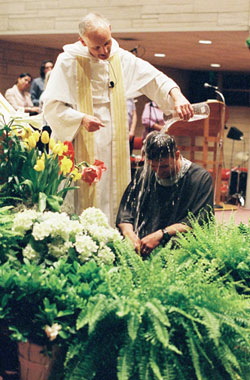 Dominican Father Robert Keller, pastor of the St. Paul Catholic Center in Bloomington, baptizes William Valentine during his parish’s Easter Vigil on April 11. (Submitted photo) 