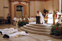 Archbishop Daniel M. Buechlein and concelebrating priests kneel in prayer for the litany of the saints with the assembly as Deacons Jeremy Gries, from left, John Hollowell and Peter Marshall lay prostrate on the marble during the ordination Mass on June 6 at SS. Peter and Paul Cathedral in Indianapolis. Benedictine Father Julian Peters, administrator pro-tem of Cathedral Parish and the master of ceremonies, and seminarian Martin Rodriguez kneel to the right of the archbishop. (Photo by Mary Ann Wyand) 