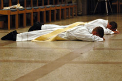 Transitional Deacons Sean Danda, front, and Christopher Wadelton lay prostrate on the marble floor of SS. Peter and Paul Cathedral on June 27 as Archbishop Daniel M. Buechlein, concelebrating priests and lay people kneel in prayer during the litany of the saints. (Photo by Mary Ann Wyand) 