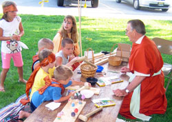 Omer Cord, right, helps children learn the trade of carpentry in the Roman village marketplace at the vacation Bible school held on July 6-10 at St. Vincent de Paul Parish in Shelby County. (Photo by Gary Lindberg)