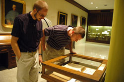 Seminarians Phillip Rahman, left, and David Proctor peer into a display case in the Old Cathedral Library in Vincennes that houses many of the books of Bishop Bruté and early documents of the Diocese of Vincennes, which later became the Archdiocese of Indianapolis. (Photo by Sean Gallagher)
