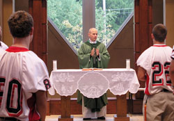Father John Hollowell, chaplain and assistant football coach at Cardinal Ritter High School in Indianapolis, celebrates Mass with the Cardinal Ritter varsity football team on Sept. 25 before their game against Park Tudor School. (Photo by John Shaughnessy) 