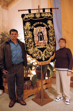 St. Mary parishioner Jaime Torpoco of Indianapolis, left, who is a native of Peru, and his mother, Jobita Oscorima of Lima, Peru, pose for a photograph beside an ornate, handmade banner honoring St. Martin de Porres after the saint’s feast day Mass on Nov. 3 at SS. Peter and Paul Cathedral in Indianapolis. The religious banner was created by one of their relatives as well as several Peruvian youths in Lima. (Photo by Mary Ann Wyand)