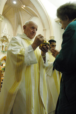 Retired Father Frank Eckstein gives Communion to a worshipper at a Feb. 26, 2007, Mass at St. Louis Church in Batesville. In retirement, Father Eckstein has been the sacramental minister for eight years at St. Charles Borromeo Parish in Milan and St. Pius Parish in Ripley County. (File photo by Sean Gallagher)