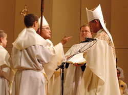Archbishop Charles J. Chaput of Denver speaks to Bishop Paul D. Etienne after the newly ordained bishop of Cheyenne, Wyo., placed a miter on his head for the first time. Archbishop Chaput is assisted by, from left, altar server Zach Flanagan, a member of Our Lady of Perpetual Help Parish in New Albany, and Deacon Charles Parker of the Denver Archdiocese. (Photo by Sean Gallagher)