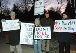 Amnesty International members Jared Carter of Indianapolis, from left, Ashley Kincaid of Avon, Michael Hartt of Indianapolis and Karen Burkhart, the Indiana death penalty abolition coordinator for Amnesty International and member of St. Susanna Parish in Plainfield, hold signs on Dec. 10 in front of the Governor’s Residence in Indianapolis indicating their opposition to capital punishment and the execution of Matthew Wrinkles. (Photo by Mary Ann Wyand)