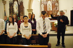 Father John Meyer, right, the pastor of Prince of Peace Parish in Madison, blesses teenagers who were preparing to participate in the 37th annual March for Life in Washington during a Jan. 17 prayer service at St. Patrick Chapel in Madison. Youth ministry coordinator Joe Stilwell, second from right, also teaches religion classes at Shawe Memorial Jr./Sr. High School in Madison. (Photo by Mary Ann Wyand)