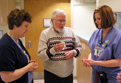 As an extraordinary minister of holy Communion, Gene Caviston brings Communion to hospital patients and staff members at St. Francis Hospital in Indianapolis. Here, Caviston offers a prayer before giving Communion to two nurses in the hospital’s labor and delivery unit, Amelia Titsworth, left, and Lisa Bauer. (Photo by John Shaughnessy)
