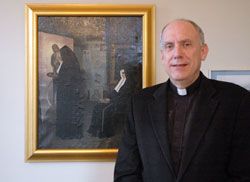 Father Stephen Giannini stands in front of of a painting by noted Hoosier artist Richard Buckner Gruelle which was found last fall in poor condition in a storage room at St. John the Evangelist Parish in Indianapolis. It was restored to its current condition by Sue McCallister, a member of St. Agnes Parish in Nashville. (Photo by Sean Gallagher)