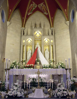 Red and white banners flow down from a statue of Jesus to make it appear like the image of Divine Mercy in 2008 in the sanctuary of St. Vincent de Paul Church in Bedford. Parishes across the archdiocese will hold Divine Mercy services on April 11, which is Divine Mercy Sunday. (Submitted photo)