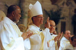 Bishop Paul D. Etienne of Cheyenne, Wyo., center, acknowledges the applause of the congregation during the archdiocesan chrism Mass celebrated on March 30 at SS. Peter and Paul Cathedral in Indianapolis. Joining in the applause are deacons Emilio Ferrer-Soto, left, and David Henn. Bishop Etienne was a priest of the archdiocese for 17 years before Pope Benedict XVI appointed him the eighth bishop of Cheyenne last October. (Photo by Sean Gallagher)