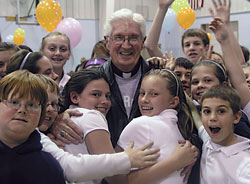 Students at St. Roch School in Indianapolis rejoice with Father James Wilmoth following a school-wide tribute on April 8 that celebrated their pastor. The school celebration recognized Father Wilmoth’s selection as one of the 10 priests from across the United States who recently received the Distinguished Pastor Award from the National Catholic Educational Association. (Photo by John Shaughnessy)
