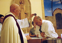 Father John McCaslin baptizes Wallace “Wally” Miller of Indianapolis during the Easter Vigil Mass on Holy Saturday, April 3, at St. Anthony Church in Indianapolis. Miller’s wife, Debbie, was his Rite of Christian Initiation of Adults sponsor. Father McCaslin is the pastor of St. Anthony Parish and administrator of Holy Trinity Parish in Indianapolis. (Photo by Mary Ann Wyand)