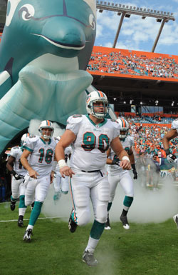 Miami Dolphins defensive lineman Ryan Baker, No. 90, runs out on the football field before a 2009 game. A 2004 graduate of Bishop Chatard High School in Indianapolis, he will return to his alma mater on June 26 to lead the inaugural Ryan Baker Football Camp. (Photo courtesy the Miami Dolphins)