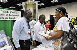 Holy Cross Brother Roy Smith, left, and his sister, Sister Demetria Smith, a member of the Missionary Sisters of Our Lady of Africa, talk with Karlynn Jordan, right, of Indianapolis at the Church’s “Faith and Family” booth on July 17 during the Indiana Black Expo’s 40th annual “Summer Celebration” at the Indiana Convention Center in Indianapolis. (Photo by Mary Ann Wyand)