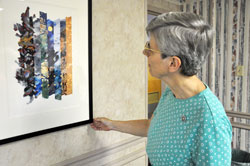 Benedictine Sister Carol Falkner, administrator of the Benedict Inn Retreat and Conference Center in Beech Grove, looks at a print of an illustration for the Book of Genesis from The Saint John’s Bible exhibit on Aug. 2. The exhibit features artwork and calligraphy by Welsh artist Donald Jackson as well as an exhibit of historic religious manuscripts on loan from John Lawrence of Evansville, Ind., who is an art conservator and consultant on Medieval and Renaissance artifacts. The Bible exhibit is free and on display from Aug. 6-29. (Photo by Mary Ann Wyand)