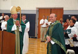 Archbishop Daniel M. Buechlein leads members of SS. Francis and Clare of Assisi Parish in Greenwood in applauding the parish’s pastor, Father Vincent Lampert, on Aug. 8 for his hard work and ministry in leading the faith community during its rapid expansion over the past four years. Standing behind Archbishop Buechlein, from left, deacons Stephen Hodges and Ronald Reimer join in the applause. (Photo by Sean Gallagher)