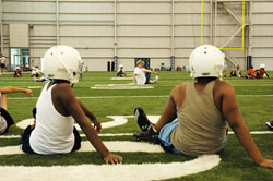Football players from the Mother Theodore Catholic Academies do stretches during a practice on Aug. 18 at the indoor facility where the Indianapolis Colts prepare for their games. The Mother Theodore Catholic Academies will field combined football teams for the first time this year, thanks to funds from a Super Bowl raffle made possible by Indianapolis Colts’ president Bill Polian. (Photo by John Shaughnessy)