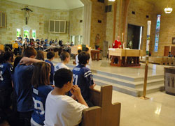 Students at Little Flower School in Indianapolis kneel in prayer during a Feb. 5, 2010, Mass at St. Therese of the Infant Jesus (Little Flower) Church while Father Robert Gilday, pastor of the parish, prays the eucharistic prayer. During the Mass, students gave cards of appreciation to Father Gilday. Making the cards was part of a parish-wide program to help all parishioners learn about the sacraments. (File photo by Sean Gallagher)