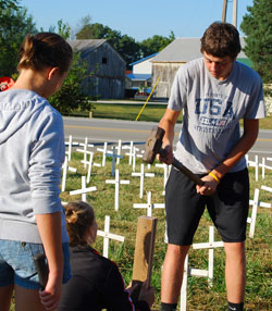 St. Joseph parishioner Brian Weigel of St. Leon pounds a cross into the ground with the help of another youth in the parish on Sept. 18 along Route 1 just south of Interstate 74 in Dearborn County. The “Cemetery of the Innocents” display of 4,000 crosses represents the number of babies that die in legalized abortion each day in the United States. The traveling pro-life exhibit will be on display in St. Leon through Oct. 2. (Submitted photo)