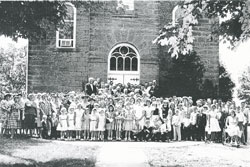 Members of Holy Cross Parish in St. Croix in the Tell City Deanery pose in front of their parish church in 1960 during a celebration of the centennial of its founding. Current parishioners celebrated the 150th anniversary of its founding with a festive Mass on Oct. 10. (Submitted photo)