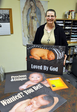 Patricia Arthur, the administrative assistant of the archdiocesan Office for Pro-Life Activities, displays three of the respect life signs that will be carried by people during the Jan. 24 pro-life march from SS. Peter and Paul Cathedral to the Veterans Memorial Plaza in downtown Indianapolis. (Photo by Mary Ann Wyand)