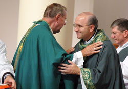 Archbishop Daniel M. Buechlein, left, and Father Vincent Lampert, center, exchange the sign of peace during an Aug. 8, 2010, Mass at SS. Francis and Clare of Assisi Church in Greenwood. Father Lampert is the pastor of the Indianapolis South Deanery parish. Deacon Ronald Reimer, who ministers at SS. Francis and Clare, stands at right. (File photo by Sean Gallagher)