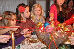 Anna Johnson, from left, Caroline Burns, Mary Monesmith and Kate Johnson of Indianapolis pull ribbons tied to Christmas ornaments from a crystal punch bowl to see if they will be crowned the “queen” of the tea party hosted by Leigh Dunnington-Jones to celebrate the feast of the Epiphany of the Lord on Jan. 6. (Photo by Mary Ann Wyand)