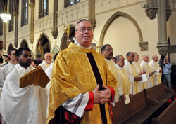 Bishop-designate Christopher J. Coyne smiles at family members and friends from the Archdiocese of Boston as he processes up the aisle on March 2 at St. John the Evangelist Church in Indianapolis for his episcopal ordination Mass. Walking behind Bishop Coyne is Cyrus Sethna of St. Margaret Mary Parish in Westwood, Mass., who—along with his twin brother, Reggie—assisted as an altar server during the liturgy. (Photo by Mary Ann Wyand)