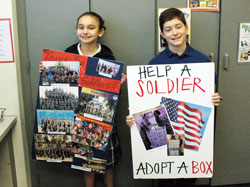 Fifth-grade students Susanna Tsueda and John Morrissey display posters that encourage fellow students at St. Simon the Apostle School in Indianapolis to collect candy, cookies and gifts for American soldiers serving overseas. (Photo by John Shaughnessy)