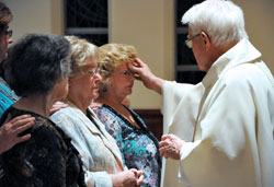 Msgr. John Duncan, chaplain at the St. Augustine Home for the Aged in Indianapolis, places chrism oil on resident Jackie Cooper’s forehead as part of the sacrament of confirmation during the Easter Vigil on April 23 at the chapel in the home operated by the Little Sisters of the Poor. St. Augustine Home residents Rita Flowers, left, and Helen Marsh were also confirmed and received first holy Communion. (Photo by Mary Ann Wyand)