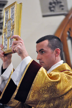 Transitional Deacon Dustin Boehm holds a Book of the Gospels during the March 2 ordination of Bishop Christopher J. Coyne, auxiliary bishop and vicar general, at St. John the Evangelist Church in Indianapolis. Deacon Boehm is scheduled to be ordained a priest at 10 a.m. on June 4 at SS. Peter and Paul Cathedral in Indianapolis. (File photo by Mary Ann Wyand)