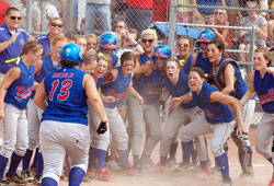 Members of the softball team of Roncalli High School in Indianapolis crowd around home plate and cheer for teammate Andrea Rodriguez after she hit a three-run home run in the first inning of their June 11 Indiana High School Athletic Association 3A championship game against Andrean High School in Merrillville, Ind. The game was played at Ben Davis High School in Indianapolis. Roncalli defeated Andrean 8-0. (Photo by Sean Gallagher)