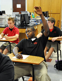 Cardinal Ritter High School student Jamieson Rhodes holds up his hand to ask a question in a chemistry class taught by Zach Dennis during the 2010-11 school year. In the background are Evan Vinci, left, and Sam Bruns. Cardinal Ritter High School in Indianapolis is among the 62 Catholic schools in the archdiocese that have already committed to the Indiana school voucher program, which starts on July 1. (File photo by Mary Ann Wyand)