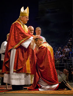 Archbishop Joseph E. Kurtz of Louisville, Ky., ordains his former vicar general, Bishop Charles C. Thompson, as the fifth bishop of Evansville, Ind., on June 29 at Roberts Municipal Stadium in Evansville. Bishop Thompson succeeds Bishop Gerald A. Gettelfinger, who is seen over the shoulder of the archbishop. Also pictured is Father Patrick Beidelman, director of liturgy for the Archdiocese of Indianapolis, who served as master of ceremonies. (Photo by Peewee Vasquez, The Message)