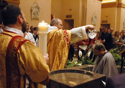 Benedictine Father Julian Peters, at the time administrator pro-tem of SS. Peter and Paul Cathedral Parish in Indianapolis, baptizes Scott Warpool during Cathedral Parish’s Easter Vigil. Then-transitional Deacon Aaron Jenkins, holding the parish’s Easter candle, stands at left. The Easter Vigil culminates the Rite of Christian Initiation of Adults, which is a primary means of adult faith formation in many parishes. (File photo by Sean Gallagher)