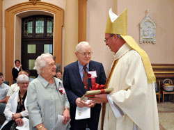 Nativity of Our Lord Jesus Christ parishioners Leona and James Schuler of Indianapolis accept a gift from Bishop Christopher J. Coyne, auxiliary bishop and vicar general, during the 28th annual archdiocesan Golden Wedding Anniversary Celebration liturgy on Sept. 18 at SS. Peter and Paul Cathedral in Indianapolis. The Schulers have been married for 69 years, and were the longest married couple attending the Mass. (Photo by Mary Ann Garber)