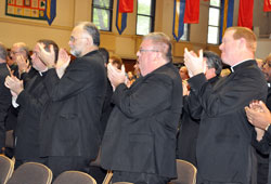 Fathers Peter Marshall, from left, James Farrell, Robert Robeson and Patrick Beidelman stand and applaud Archbishop Emeritus Daniel M. Buechlein after he announced his early retirement for health reasons during the Sept. 21 press conference at the Archbishop O’Meara Catholic Center in Indianapolis. (Photo by Sean Gallagher)