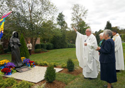 Msgr. Joseph Schaedel, pastor of St. Luke the Evangelist Parish in Indianapolis, blesses a six-foot bronze statue of St. Theodora Guérin at the conclusion of a Mass on the campus of Providence Self Sufficiency Ministries (PSSM) in Georgetown. The Mass was celebrated as part of the dedication of the campus. Assisting Msgr. Schaedel are, from left, Providence Sisters Maria Smith and Barbara Ann Zeller, president and CEO of PSSM, and Father Juan Valdes, administrator of St. Mary Parish in Lanesville. (Photo by Patricia Cornwell)
