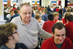 In his 50th year of Catholic education, Bob Tully still connects with students as the chairperson of campus ministry at Roncalli High School in Indianapolis. Here, Tully visits with Roncalli seniors, John Caito, left, and Sean Dunlap during a lunch period on Jan. 3. (Photo by John Shaughnessy)