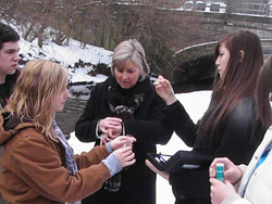 Cardinal Ritter Jr./Sr. High School science teacher Mary Pat O’Connor, center, helps seniors Charlie Elliott, from left, Claire Osecki and Vanessa Lynn collect water samples from Crooked Creek in Indianapolis during an ecology class field trip in January 2011. The students graduated on June 3. (Submitted photo)