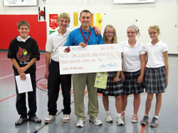 A teacher at St. Louis School in Batesville, Kyle Jolly receives a check to help with the health expenses for his first child, Landon. Students at St. Louis School raised the money, which included a donation from one girl who emptied her piggy bank. The check was presented to Jolly by St. Louis students, from left, Calvin Shenk, Jack Tonges, Sarah Meer, Abby Roell and Molly Weigel. (Submitted photo)