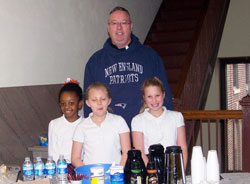 Bishop Christopher J. Coyne proudly wears his New England Patriots hoodie as he poses with St. Lawrence School students Morgen Harris, left, Ashleigh Wade and Ema O’Hara on Jan. 30. The students were serving coffee and donuts to staff at the Archbishop Edward T. O’Meara Catholic Center in Indianapolis during Catholic Schools Week. (Submitted photo)