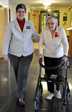 St. Paul Hermitage resident Phyllis Martin of Beech Grove walks with Benedictine Sister Rebecca Marie Fitterer, administrator of the Hermitage, who helps her walk to Mass on Feb. 2 at the Hermitage chapel. (Photo by Mary Ann Garber)