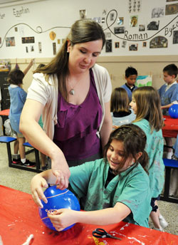 Katie Sahm, left, helps Gabriella Einterz, a third-grade student at Lumen Christi School in Indianapolis, with an art project on March 15. Sahm, who helped found Indy Catholic Artists, teaches art at the school. (Photo by Sean Gallagher)