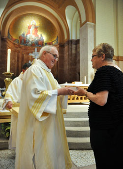 Deacon Steven Gretencord, who ministers at Sacred Heart of Jesus Parish in Terre Haute, gives blessed oils to Donna Dick-Hollingsworth, a member of Sacred Heart Parish in Clinton, during the annual archdiocesan chrism Mass celebrated on April 3 at SS. Peter and Paul Cathedral in Indianapolis. (Photo by Sean Gallagher)
