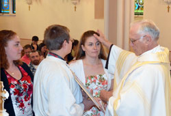Franciscan Father Humbert Moster anoints Samantha Weiler during a Rite of Baptism that took place during an April 7 Easter Vigil Mass at St. Peter Church in Franklin County. Father Humbert is the sacramental minister for the Batesville Deanery faith community. (Submitted photo)